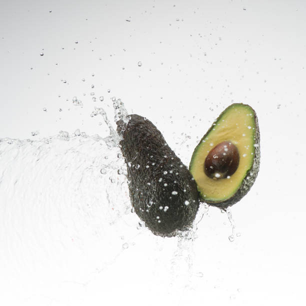 istock avocado and half avocado in water splash on white background 653533388