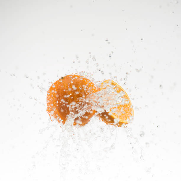 istock orange and half orange in water splash on white background 653536368