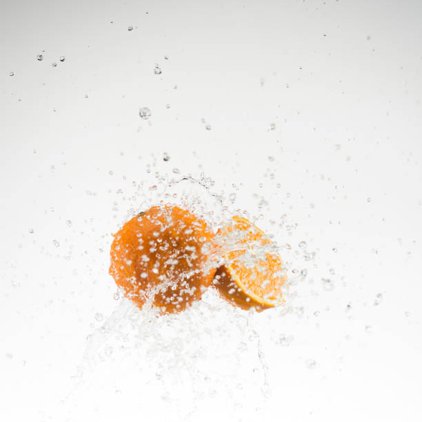 istock orange and half orange in water splash on white background 653536370