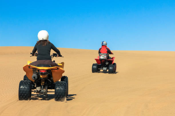 istock Quad driving people - two happy bikers in sand desert. 653538986