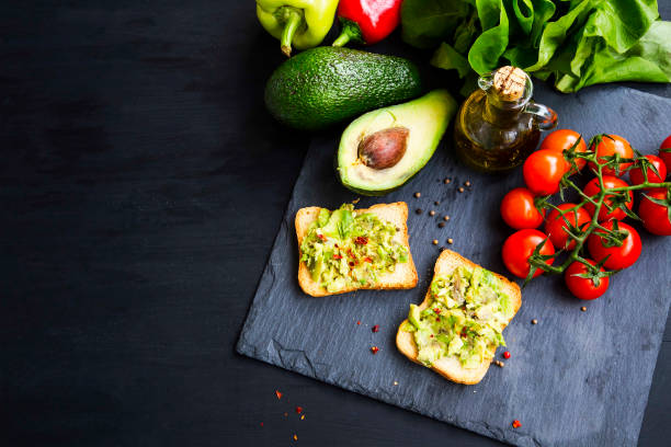 Fresh avocado on toast with chili flakes spice, cherry tomatoes, salad, pepper and avocado, overhead shot Fresh avocado on toast with chili flakes spice, cherry tomatoes, salad, pepper and avocado, overhead shot egg cherry tomato rye stock pictures, royalty-free photos & images