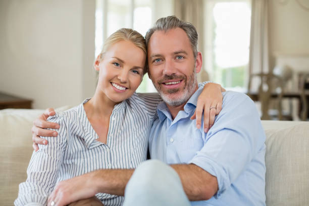istock Couple sitting on sofa with arm around in living room 653548086