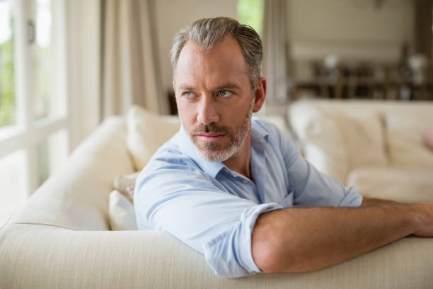 istock Thoughtful man sitting on sofa in living room 653747546