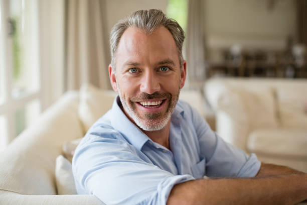 istock Smiling man sitting on sofa in living room 653747582