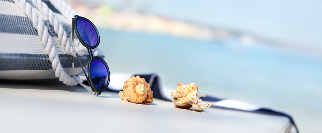 bag on the beach with sunglasses, shells and towel