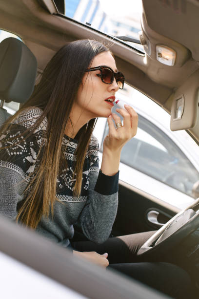 istock Young woman applying make up in car 653754382