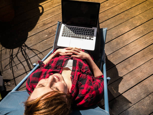 istock Young woman relaxing while sitting on a patio with her laptop 653756562