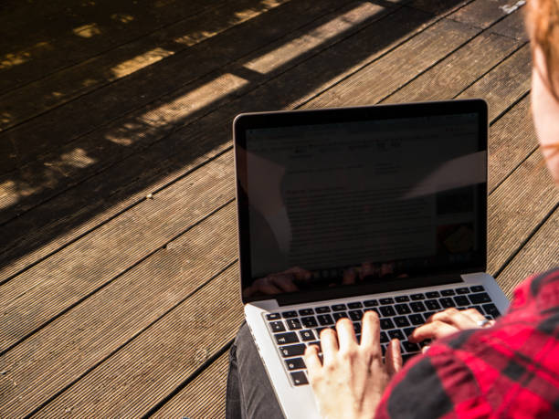 istock Young woman working while sitting on a patio with her laptop 653756774
