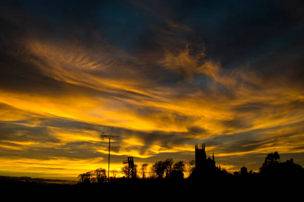 A spectacular sunset captured over the silhouettes of trees, television aerials and a cathedral.