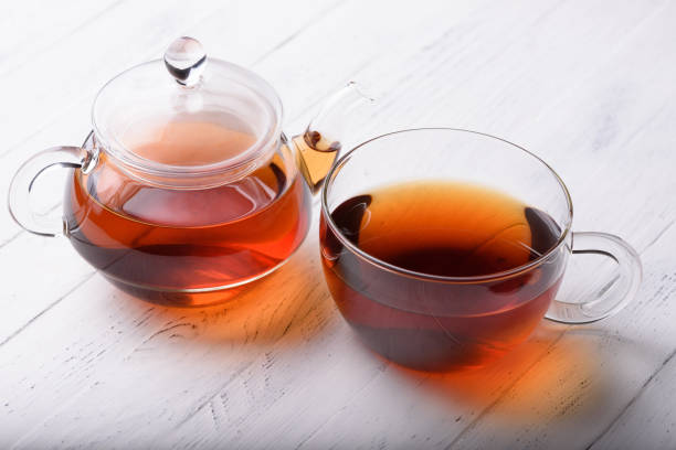 グラスティーポットとカップとホット紅茶 - 紅茶 ストックフォトと画像