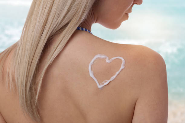 istock Woman with sun protective lotion in heart shape on shoulder. Sunburn protection 653765984