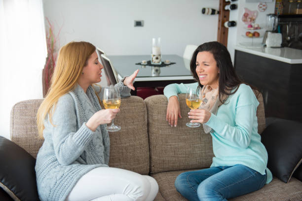 istock Two women sitting on a sofa and drinking wine 653766774