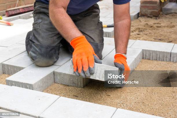 Hands Of A Builder Laying New Paving Stones Stock Photo - Download Image Now - Paving Stone, Installing, Patio