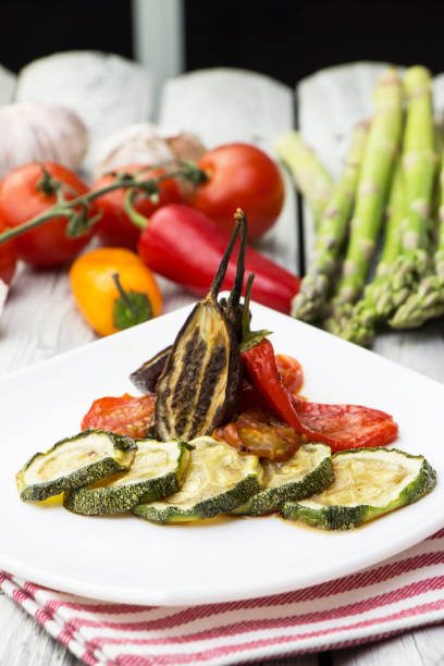 geröstetes gemüse auf dem weißen rustikalen hintergrund. zucchini, auberginen und paprika mit tomatensoße anbraten. - service bell flash stock-fotos und bilder