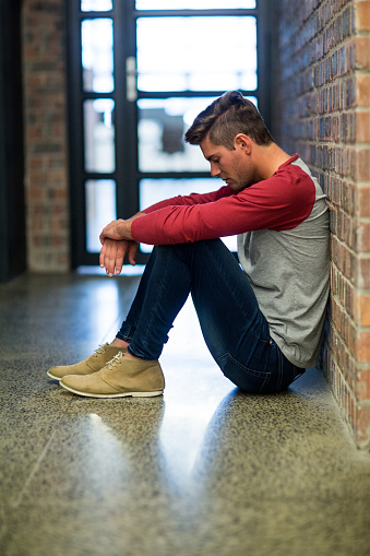 Side view of stressed man sitting in corridor