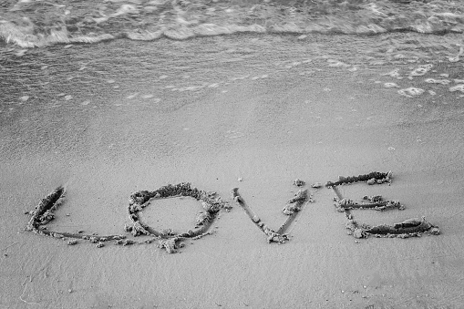On the sand written word and his love washes wave, black and white.