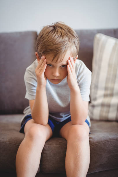 istock Portrait of upset boy sitting on sofa in corridor 653783086
