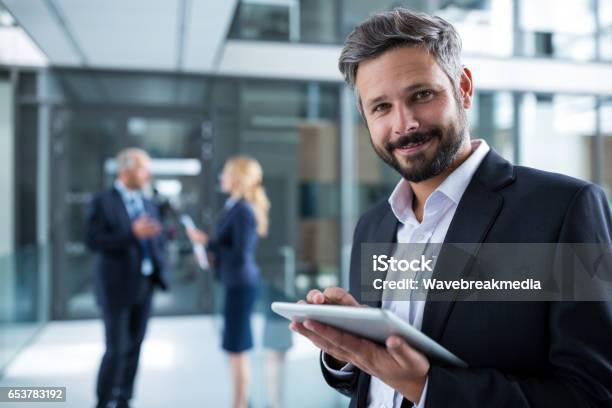 Businessman Using Digital Tablet In Office Corridor Stock Photo - Download Image Now