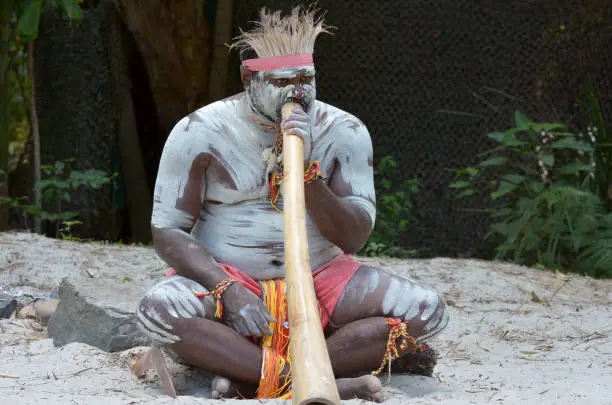 Portrait of one Yugambeh Aboriginal man play Aboriginal  music on didgeridoo, instrument during Aboriginal culture show in Queensland, Australia.