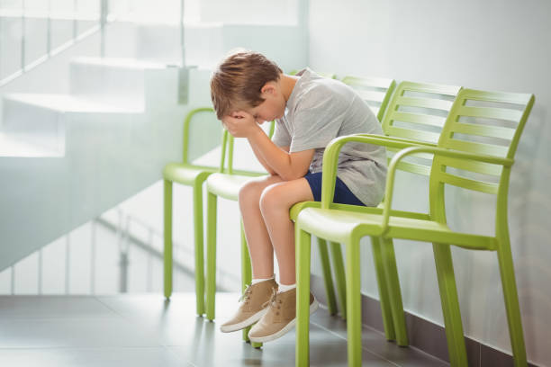 istock Upset boy sitting on chair in corridor 653787796