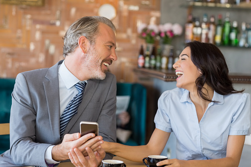 Business colleagues interacting with each other while having tea in restaurant