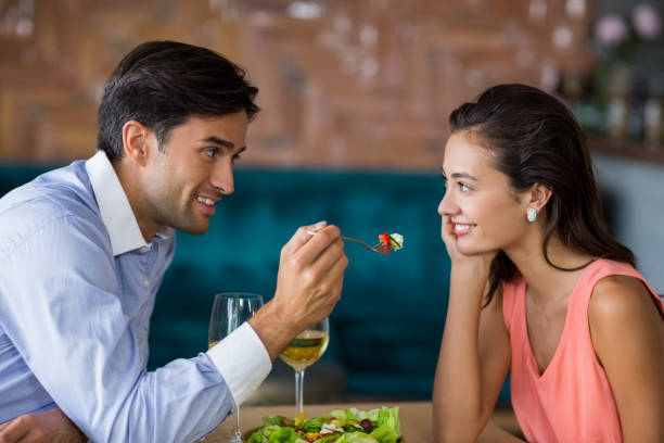 istock Smiling man feeding meal to woman 653789634