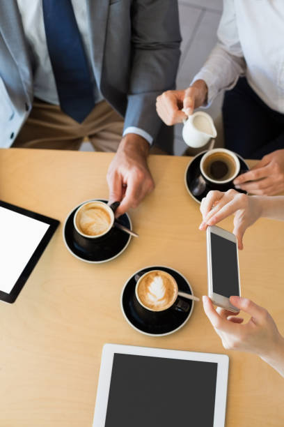 istock Colleagues having a cup of coffee while using mobile phone and digital tablet 653789914