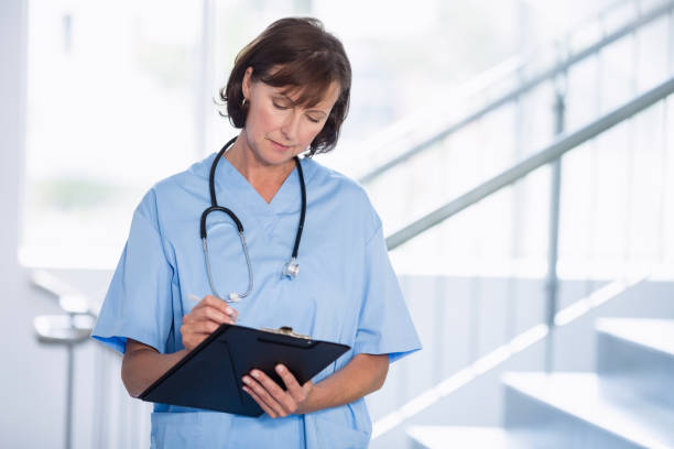istock Smiling doctor writing on clipboard in corridor 653791864