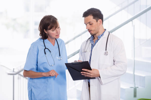 istock Nurse and doctor discussing over clipboard in corridor 653791872