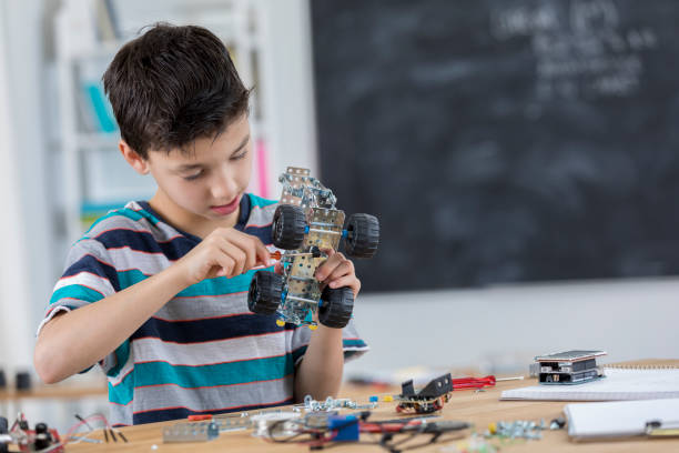 istock Schoolboy concentrates while building robot at school 653791942