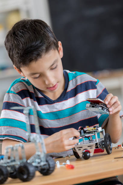 istock Hispanic schoolboy builds robot in classroom 653792046