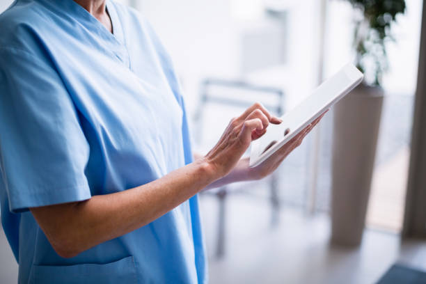 istock Nurse standing in hospital corridor using digital tablet 653792184