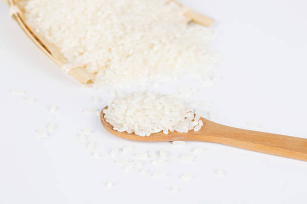 istock Rice grains closeup in a wooden spoon on a white background. 653792374