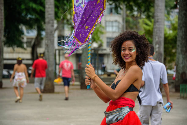 belle femme souriante aux cheveux bouclé et nez piercing, tenant le drapeau violet au bloco orquestra voadora, carnaval 2017 - parc flamengo photos et images de collection