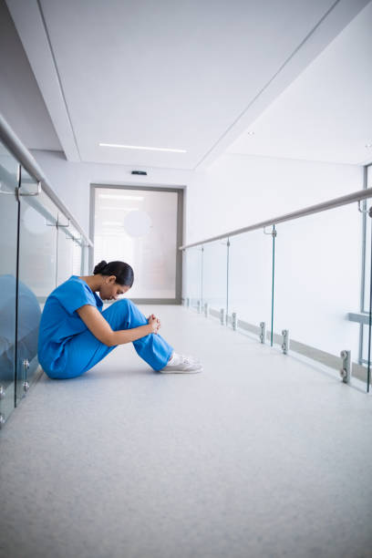 istock Sad nurse sitting on floor in corridor 653798720