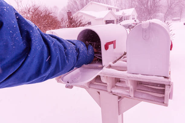 istock Man's Hand Reaching Into Winter Blizzard Snow Rural Mail Box 653800668