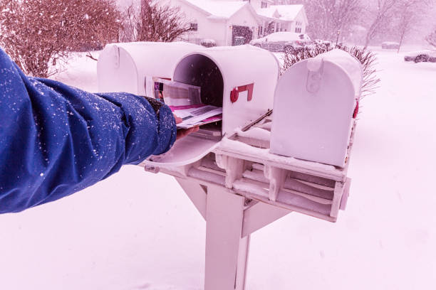 istock Man's Hand Taking Mail From Winter Blizzard Snow Rural Mailbox 653800738