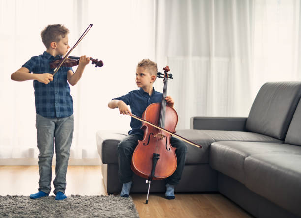 dos chicos practicando el violoncelo y violín juntos - violin family fotografías e imágenes de stock