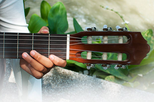 istock Young man sitting and playing guitar in the park 653806442