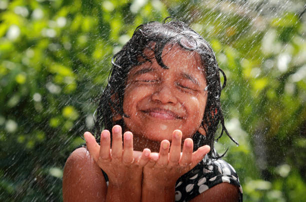 kleines mädchen spielt mit wasser - monsoon stock-fotos und bilder