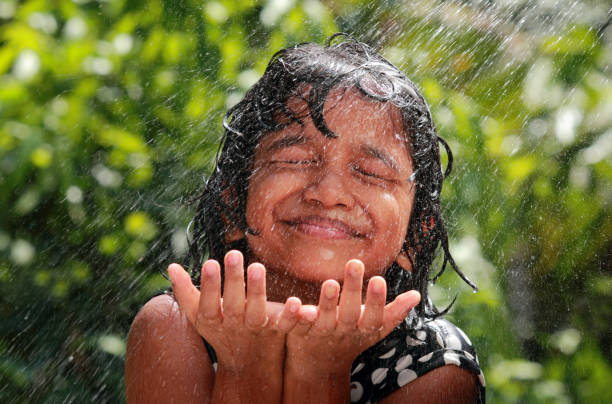 la petite fille joue avec l’eau - mousson photos et images de collection