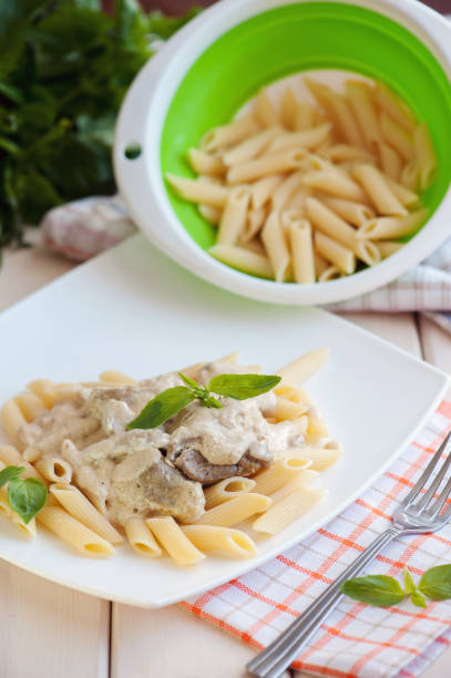 istock Penne pasta with meat and white sauce on a plate 653808454