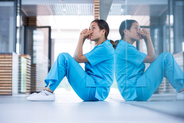enfermera preocupada sentado en el piso - doctor tired protective workwear sadness fotografías e imágenes de stock