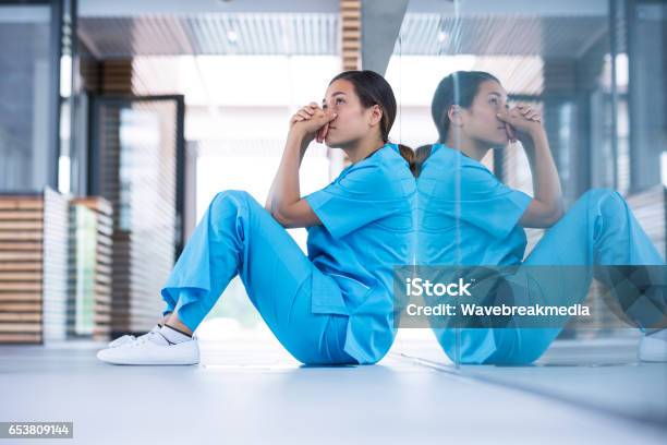 Worried Nurse Sitting On Floor Stock Photo - Download Image Now - Nurse, Emotional Stress, Tired
