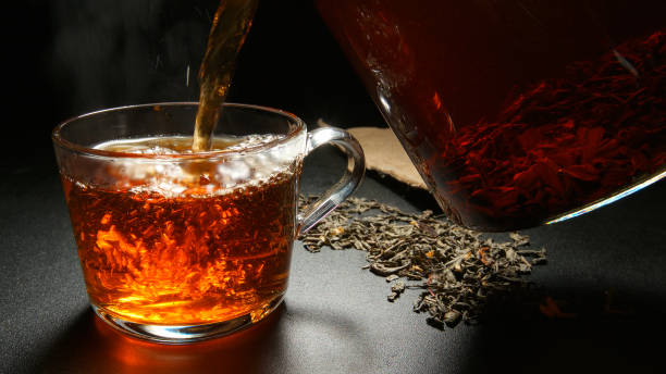istock Hot black tea pouring to a cup from a teapot 653810134