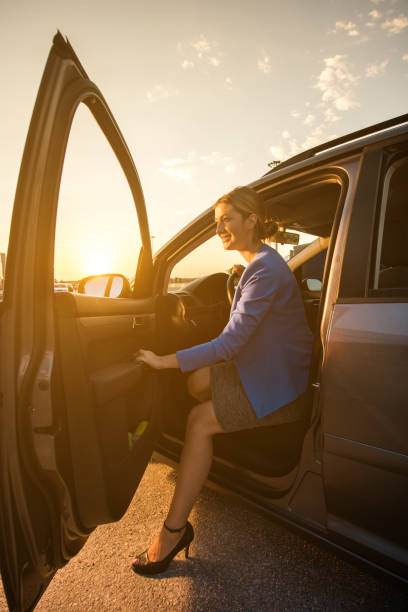 feliz empresaria salir el coche al atardecer. - car for sale fotografías e imágenes de stock