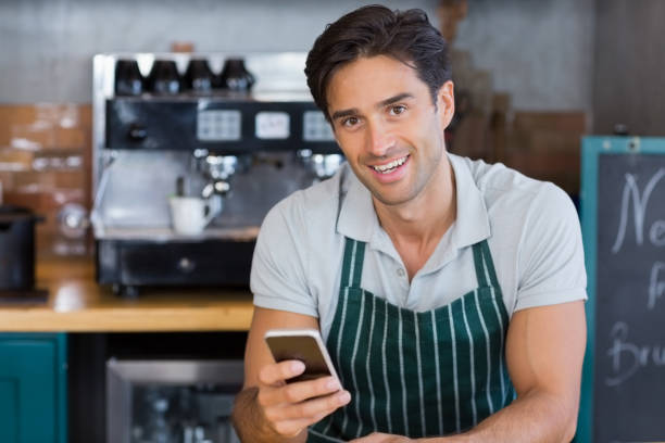 istock Portrait of smiling waitress using mobile phone 653811432