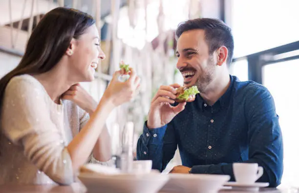 Photo of Beautiful young couple sitting in a cafe, having breakfast. Love, food, lifestyle