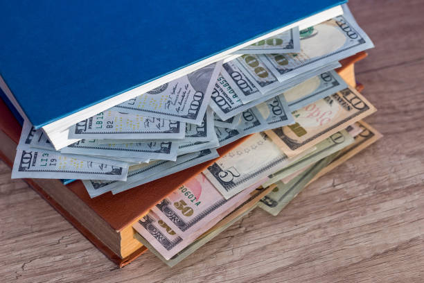 istock us 100 dollar in book on desk. 653813442