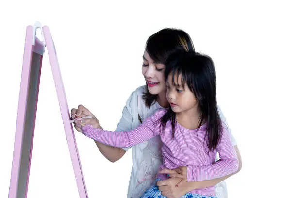 Portrait of a cute little girl learns to write on blackboard with her mother, isolated on white background